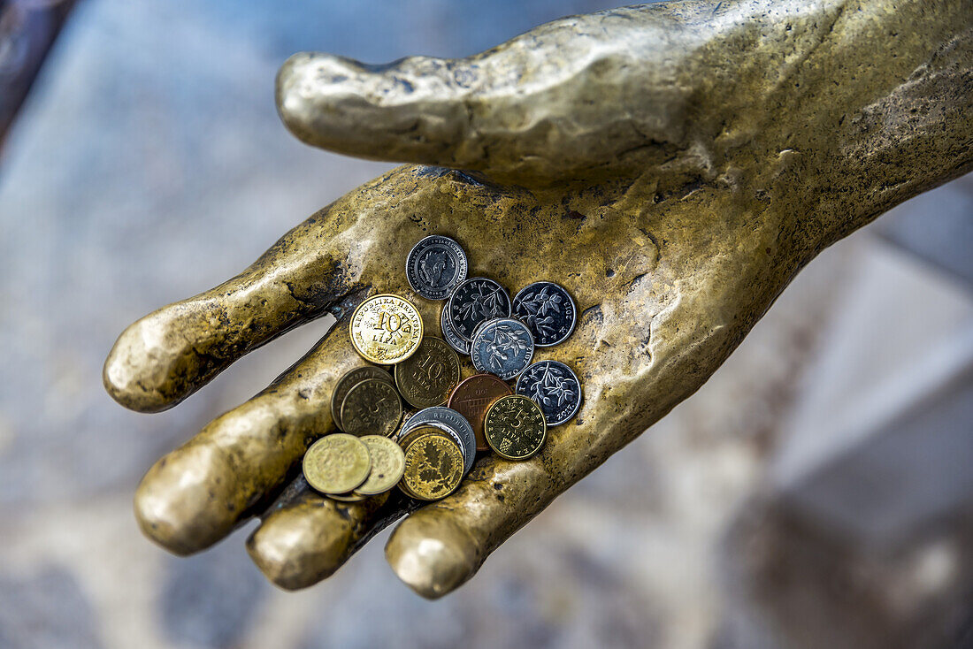 Fischerskulptur mit Münzen in der Hand in einem Hafen; Opatija, Gespanschaft Primorje-Gorski Kotar, Kroatien.