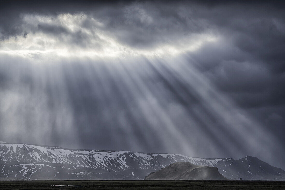 Dramatische Sonnenstrahlen brechen durch die Wolken an der Südküste Islands und schaffen eine beeindruckende Szene; Island