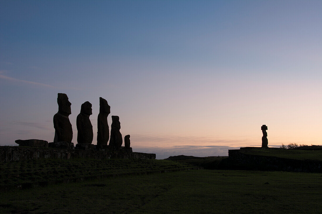 Sechs Moais, die sich gegen den frühen Morgenhimmel abheben, während die Sonne gerade aufgeht; Osterinsel, Chile.