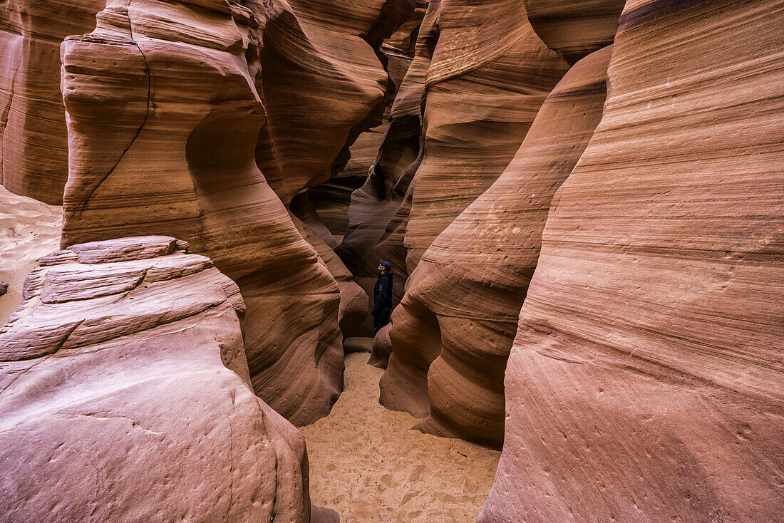Man standing in a Slot Canyon known as Canyon X, near Page; Arizona, United States of America