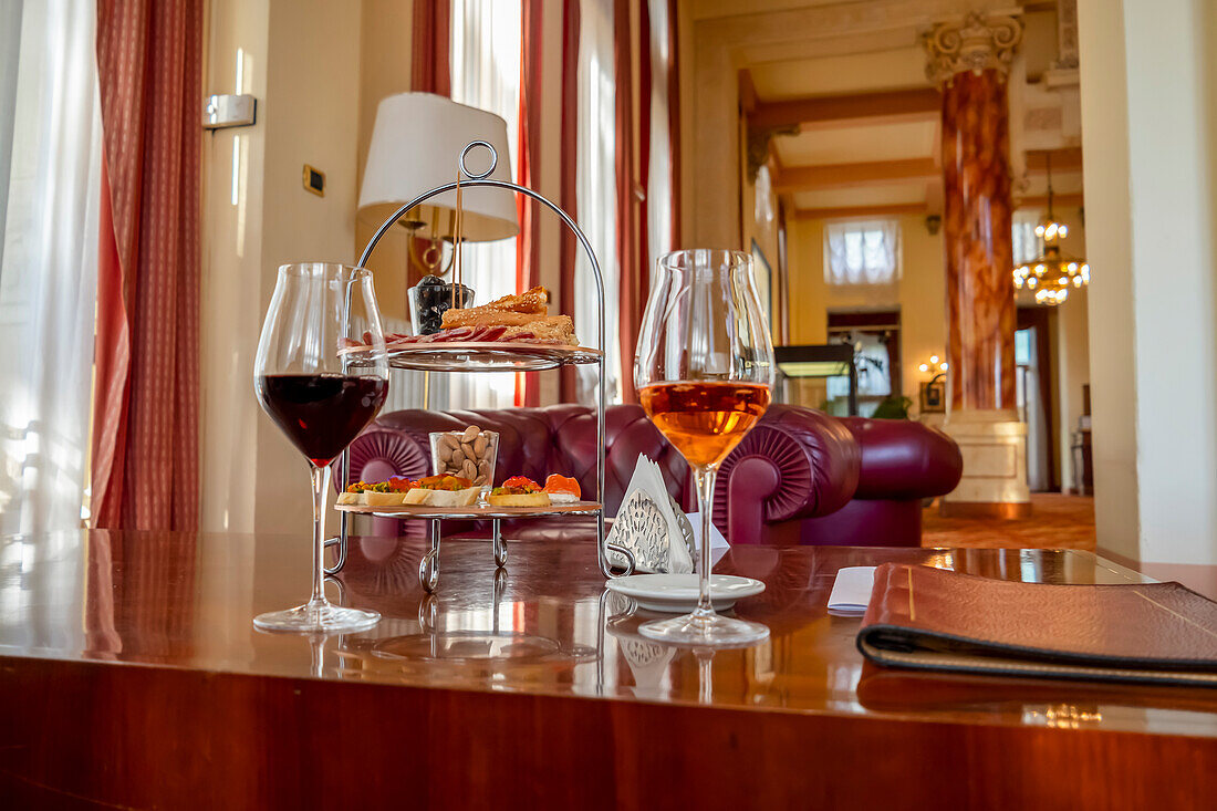 Weingläser und Hors d'oeuvres auf einem Tisch in einer Luxussuite; Varese, Lombardei, Italien.