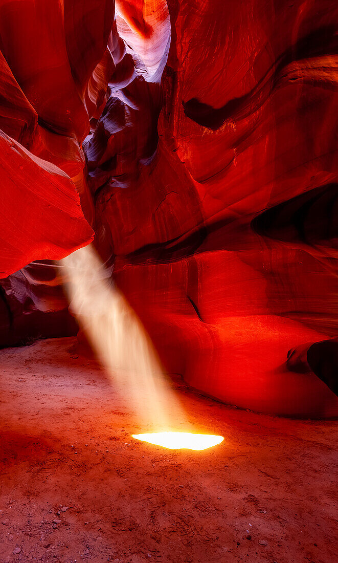 Upper Antelope Canyon with a beam of sunlight shining through a hole resembling a spotlight to the ground; Arizona, United States of America