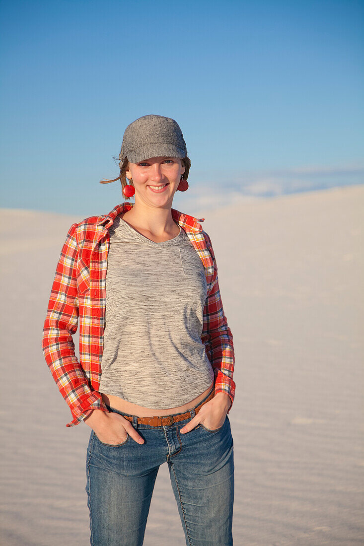 Portrait of a young woman standing on the white sand with blue sky, White Sands National Monument; Alamogordo, New Mexico, United States of America