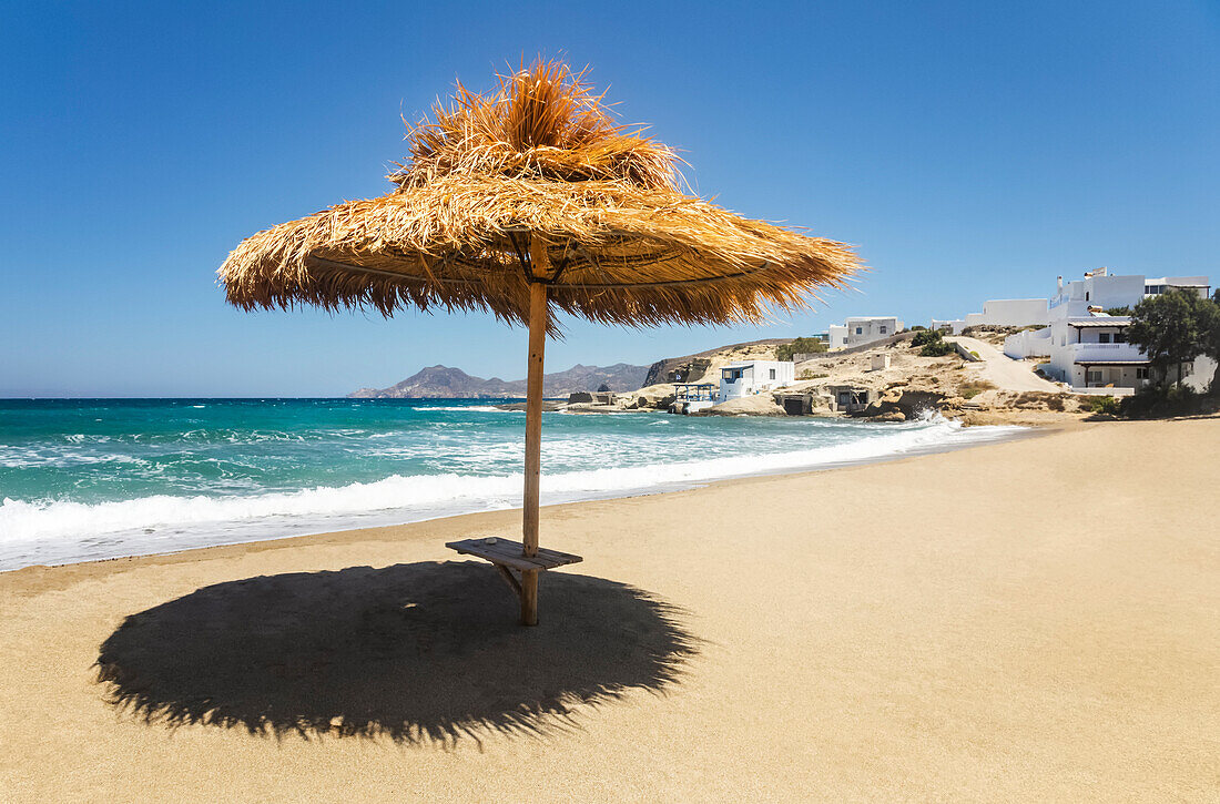 Thatch shelter casting shade onto the beach; Milos, Greece