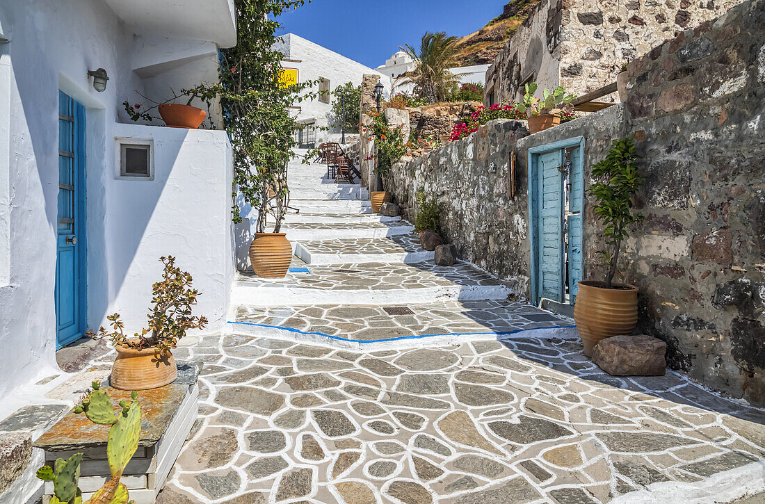 Traditionelle Häuser mit weißer Fassade und bunten Akzenten entlang eines Steinwegs; Milos, Griechenland