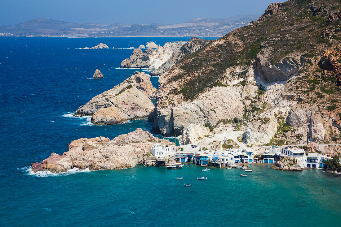 Fyropotamos Village with boats in the small harbour and a view of the rugged coastline; Fyropatamos, Milos Island, Cyclades, Greece