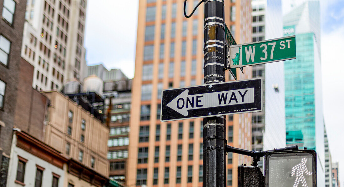 Street signs on a post, a directional one way, pedestrian walk signal and West 37th Street, Manhattan; New York City, New York, United States of America