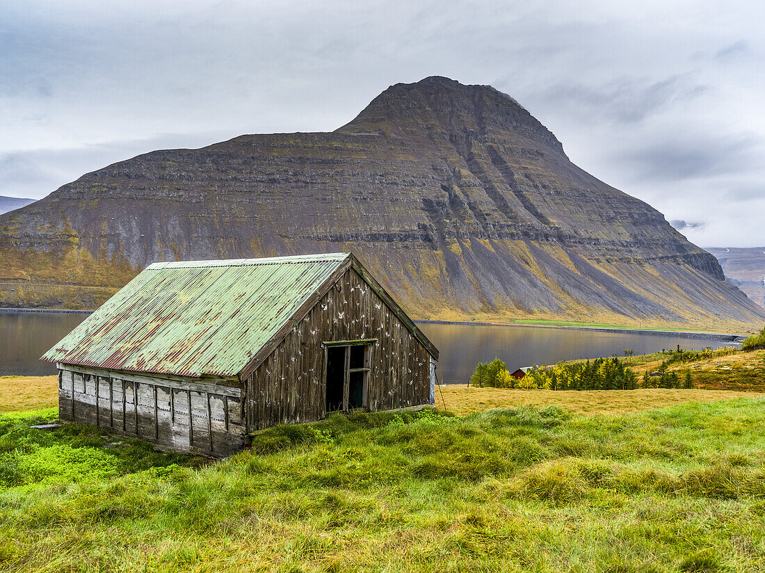 Weathered building on the water's edge of a fjord in Northwestern Iceland in the municipality of Isafjarourbaer; Isafjarourbaer, Westfjords Region, Iceland