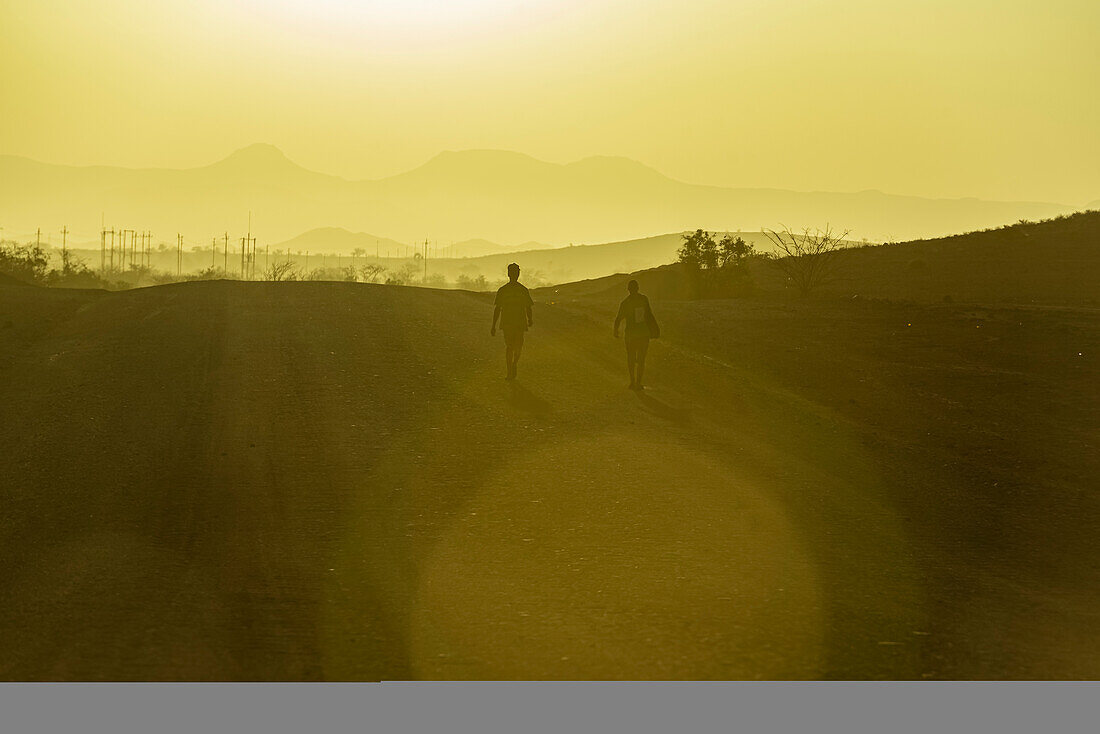 Men walking at sunset, Damaraland; Kunene Region, Namibia