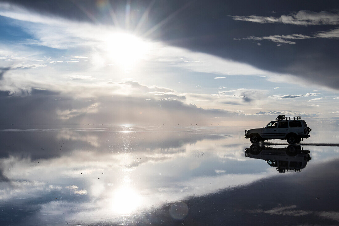 Allradantrieb und Reflexion während der Regenzeit (Dezember-Februar) im Salar de Uyuni, dem größten Salzsee der Welt; Departement Potosi, Bolivien.