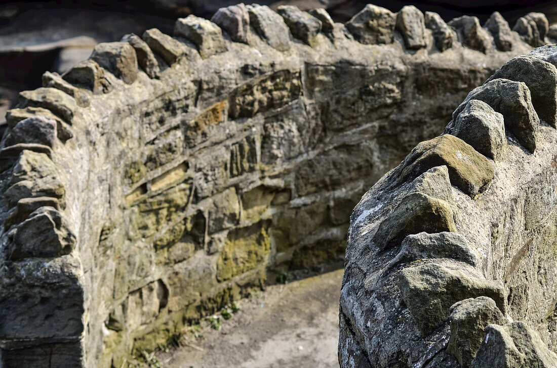 Grobe zinnenbewehrte gebogene Steinmauer, Whitley Bay; Northumberland, England