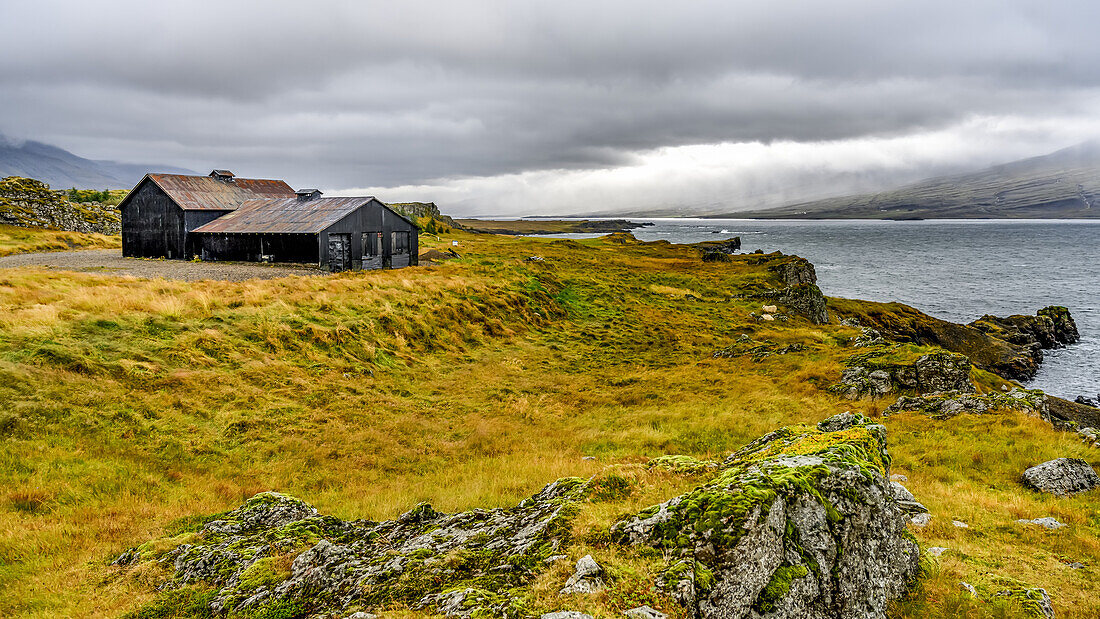 Ein Haus mit Blick auf das Wasser entlang der Küstenlinie des Fjords Berufjorour; Djupivogur, Ostregion, Island