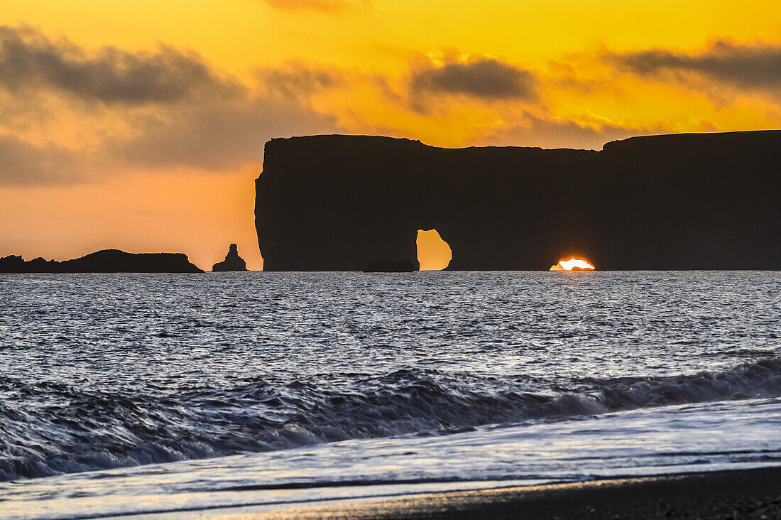 Reynisfjara, Basaltfelsen vor der Küste und ein schwarzer Sandstrand bei Sonnenuntergang; Myrdalshreppur, Südliche Region, Island