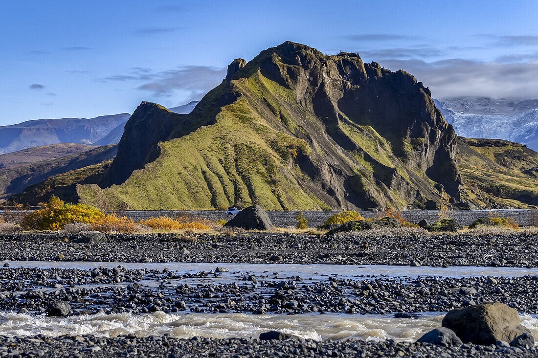 Schroffe, mit grünem Laub bedeckte Landformation mit fließendem Wasser im Vordergrund; Rangarthing eystra, Südregion, Island