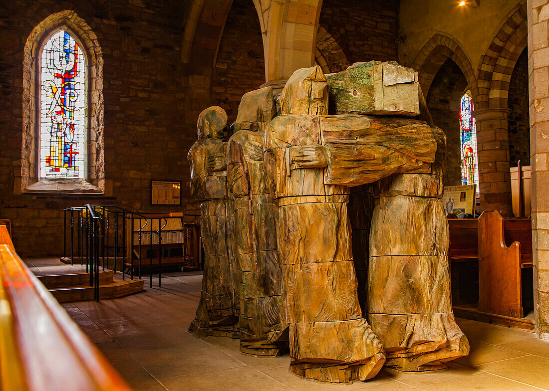 Blick von hinten auf eine geschnitzte Holzstatue, die Mönche darstellt, die den Sarg des heiligen Cuthbert auf den Schultern tragen, in der Priory von Lindisfarne: Holy Island, Northumberland, England