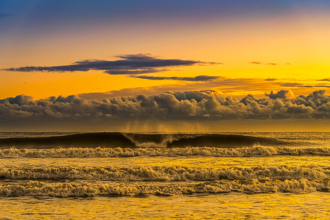 Blick auf Brecherwellen und Brandung mit tiefliegenden Wolken am Himmel bei Sonnenuntergang; South Shields, Tyne and Wear, England, Vereinigtes Königreich.