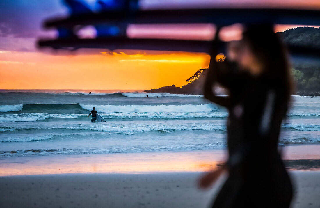 Ein wunderschöner Sonnenaufgang begrüßt die Surfer, die sich auf das morgendliche Surfen vorbereiten und hinauspaddeln; Arrawarra, New South Wales, Australien