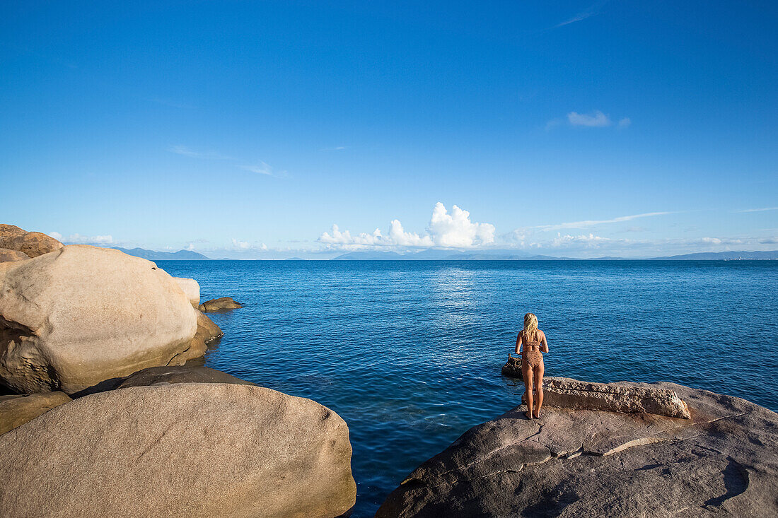 A woman looks out over the water to the horizon in Geoffrey Bay; Magnetic Island, Queensland, Australia