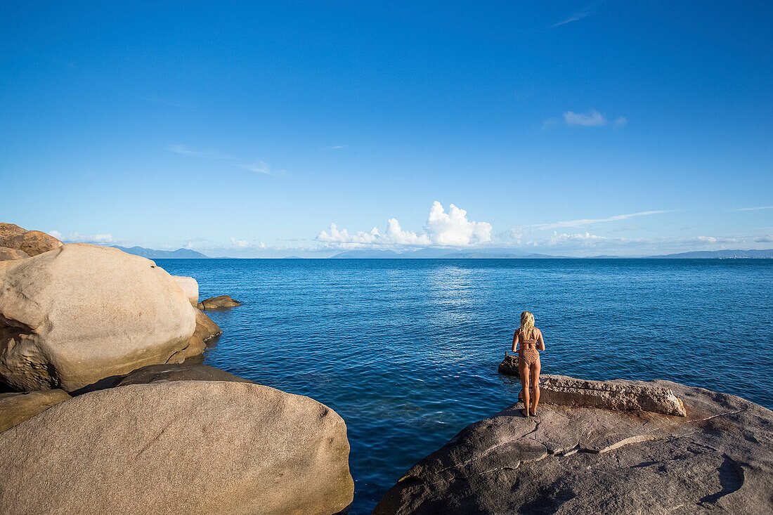 Eine Frau blickt über das Wasser auf den Horizont in der Geoffrey Bay; Magnetic Island, Queensland, Australien.