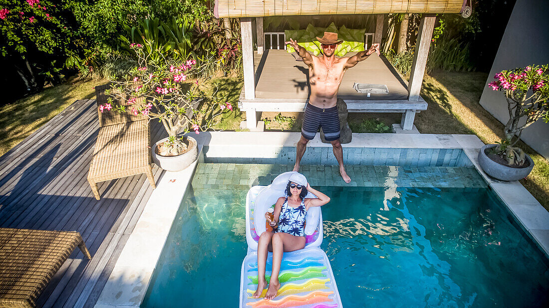 People relaxing in a pool in a Balinese villa; North Kuta, Bali, Indonesia