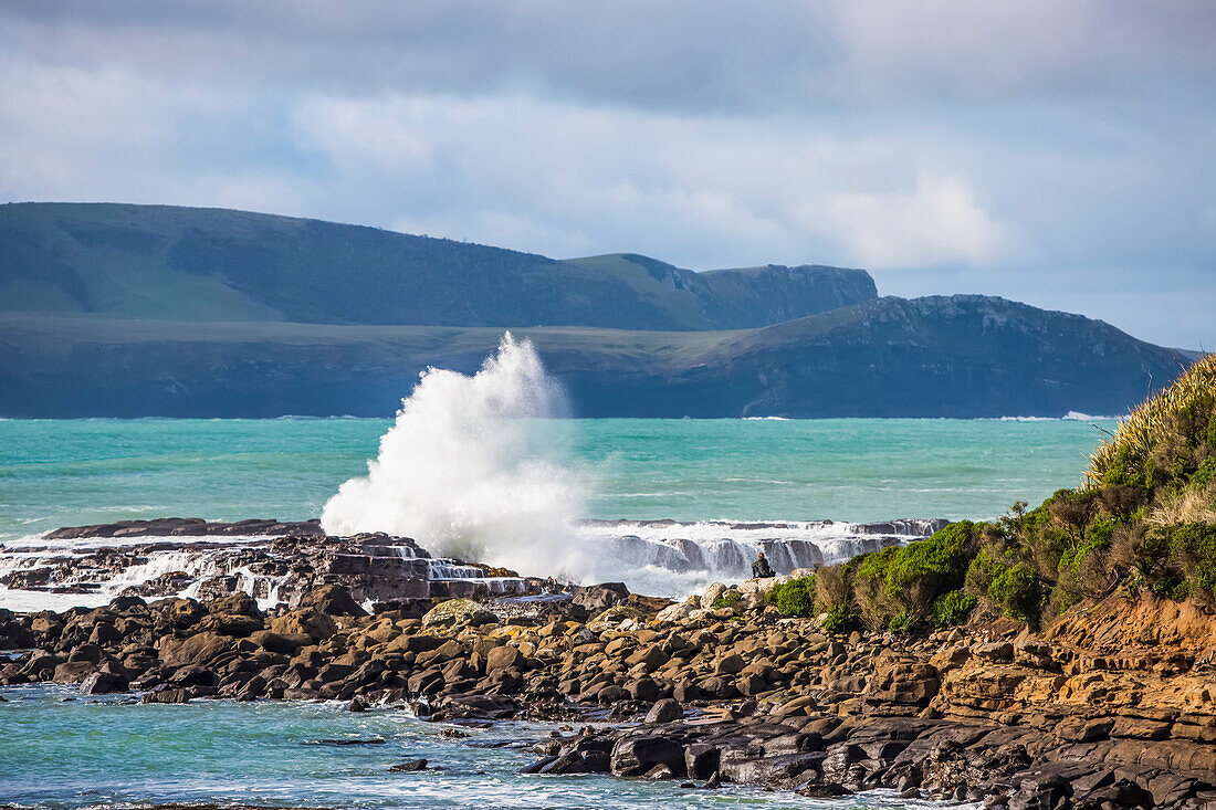 Wellen brechen an Felsen am Strand entlang der Porpoise Bay; Clutha, Southland, Neuseeland.