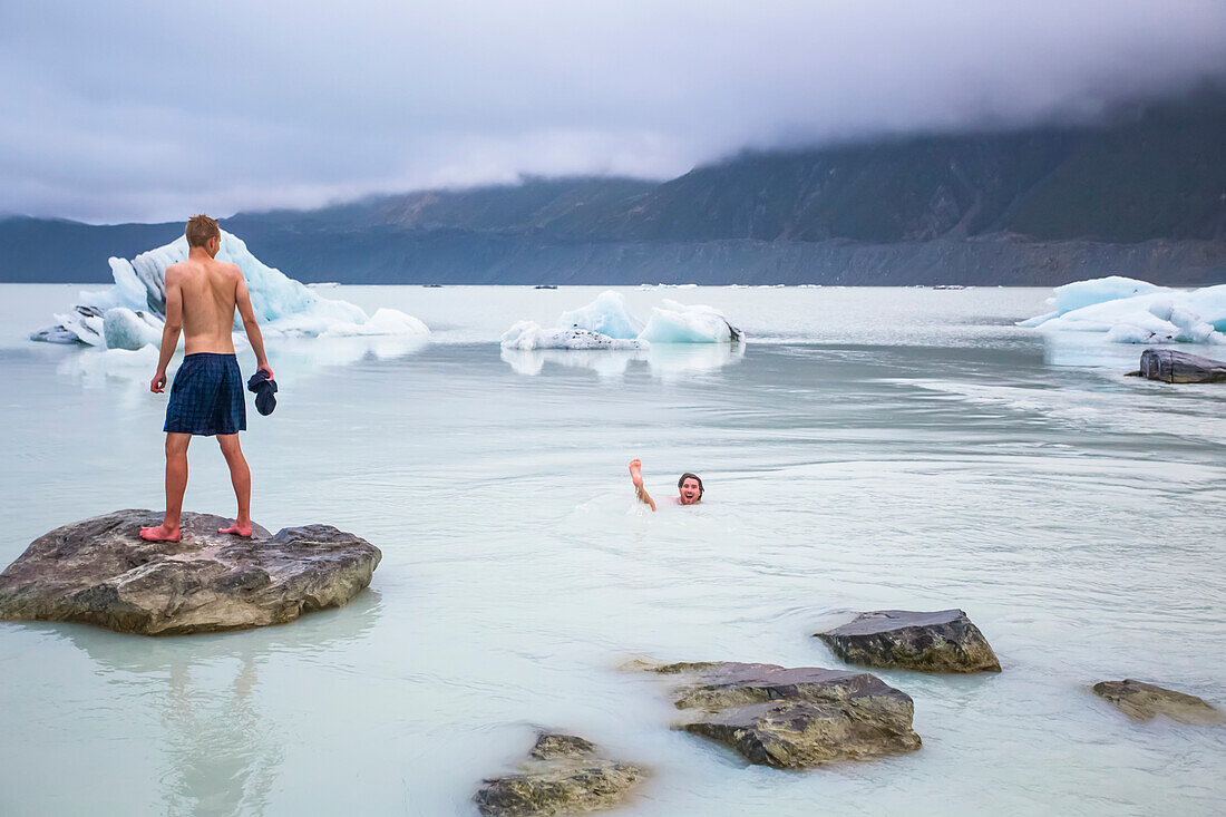 Männer schwimmen in den eisigen Gletscherseen des Mount Cook Nationalparks; Canterbury, Neuseeland.