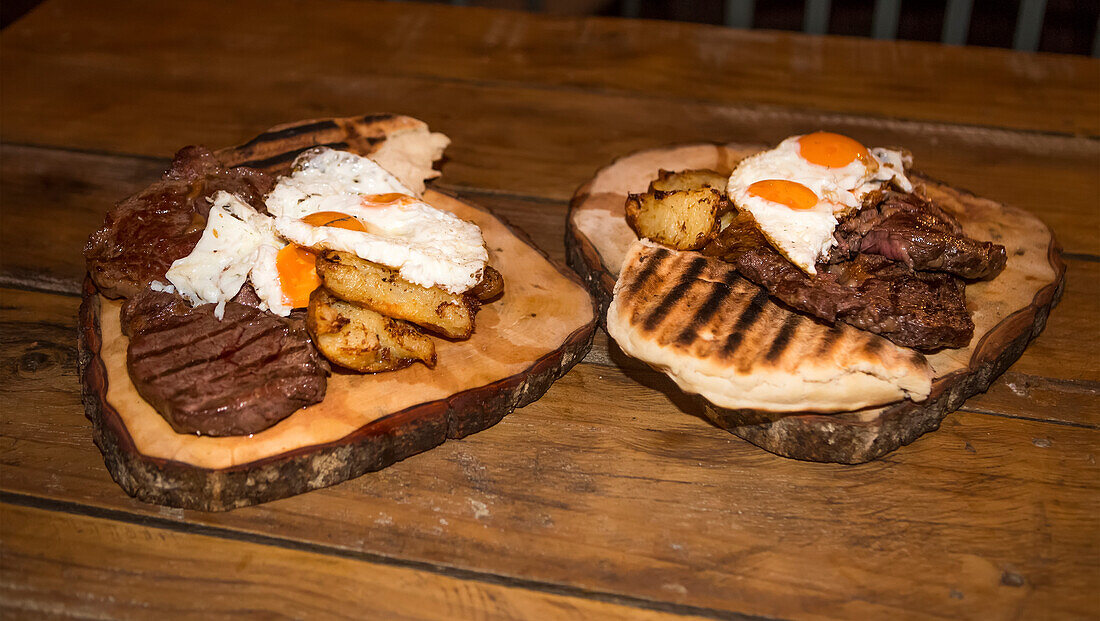 A gourmet meal of fresh meats and eggs, on a wood platter at the Blue Duck Lodge, a working cattle farm with a focus on conservation in Whanganui National Park; Retaruke, Manawatu-Wanganui, New Zealand