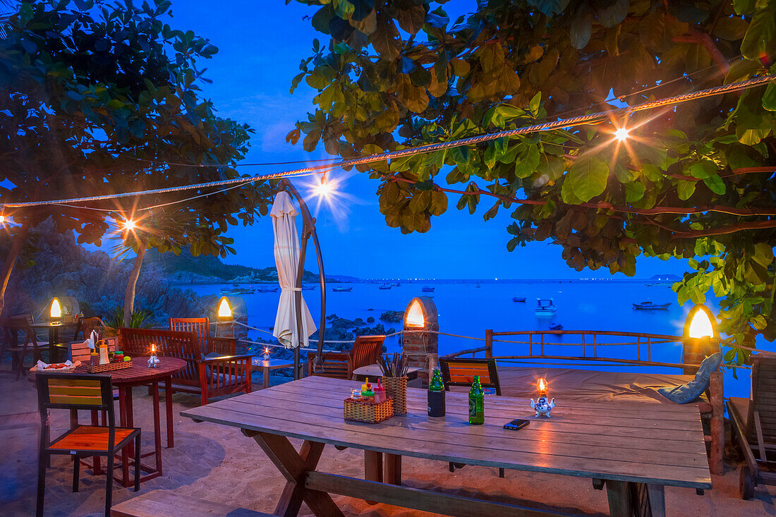 Bai Xep is a quiet remote fishing village off the tourist path, 10km from the major city of Qui Nhon. A table is set up for a beautiful sunset dinner at night; Bai Xep, Qui Nhon, Vietnam