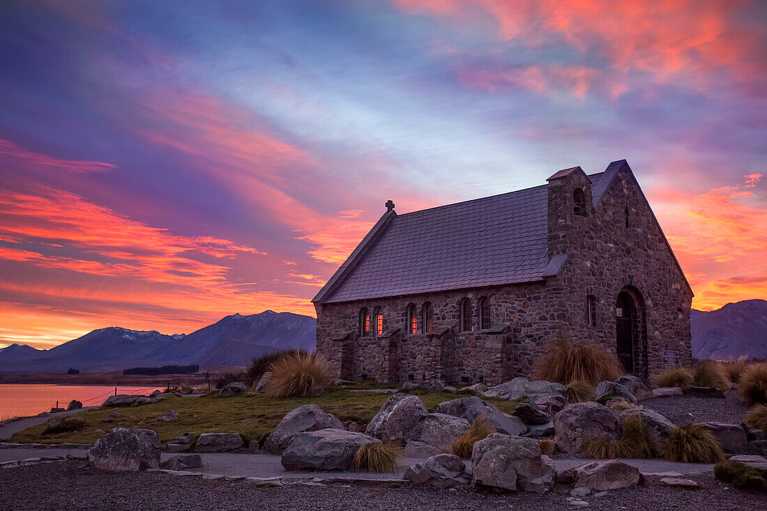 Schöner Blick über die Küste des neuseeländischen Lake Tekapo. Die berühmte Church of the Good Shepherd bei Sonnenuntergang; Lake Tekapo, Canterbury, Neuseeland