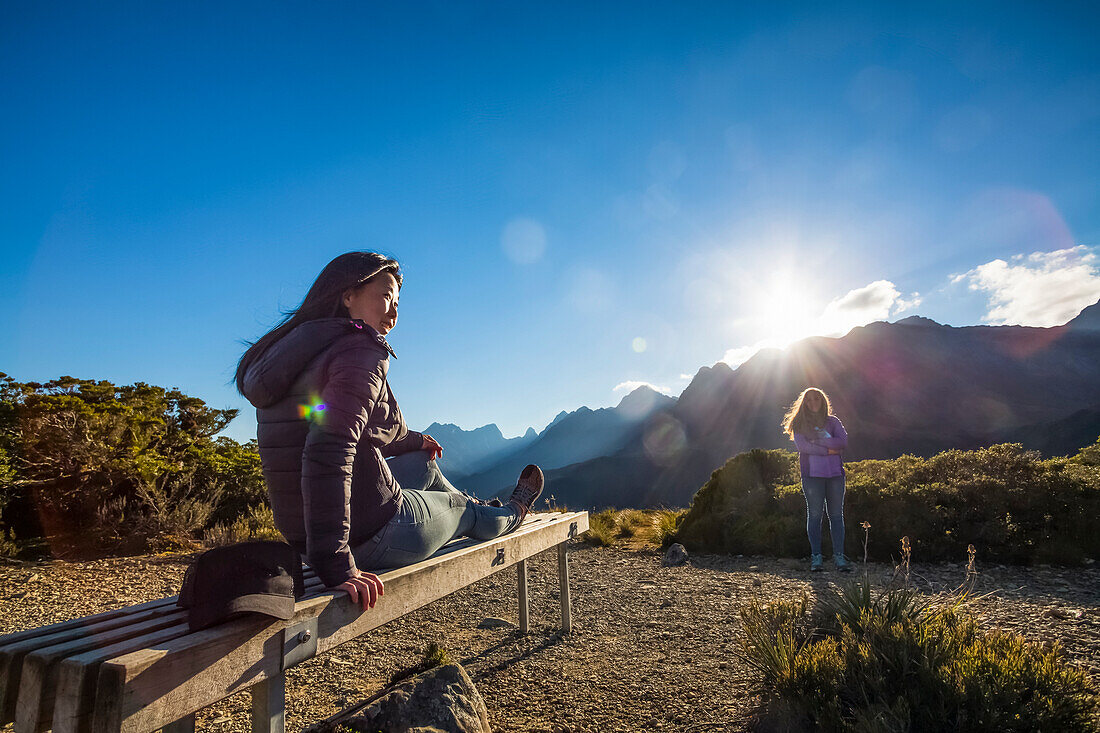 Eine Frau entspannt sich auf dem Gipfel während einer Wanderung auf dem Key Summit Track als Teil des Routeburn Tracks im Fiordland National Park; Southland, Neuseeland.