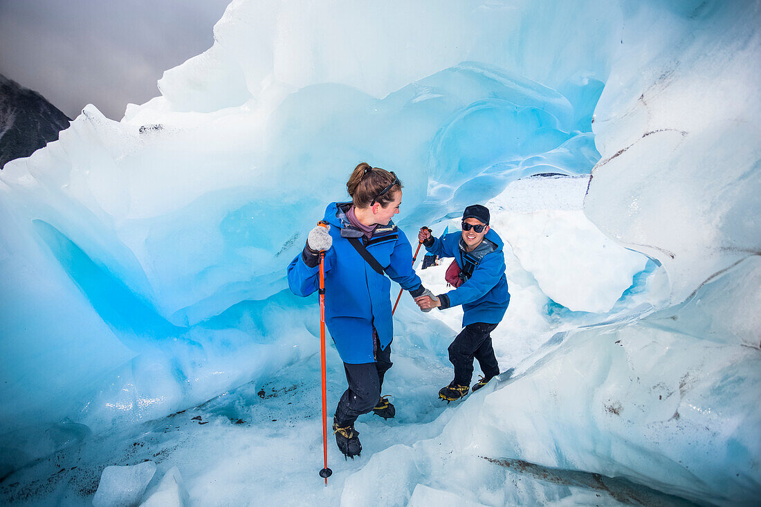 Travellers explore New Zealand's famous Franz Josef Glacier. Blue Ice, deep crevasses, caves and tunnels mark the ever changing ice; West Coast, New Zealand