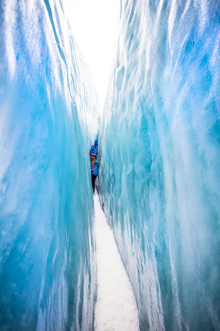 A tight squeeze for travelers exploring New Zealand's famous Franz Josef Glacier, iwth its blue Ice, deep crevasses, caves and tunnels that mark the ever changing ice formations; West Coast, New Zealand