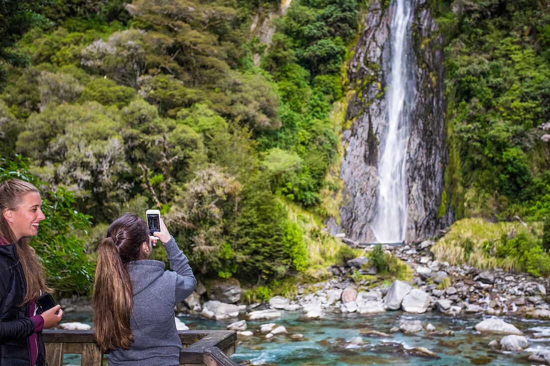 Tourists explore a random waterfall in a remote region of New Zealand's South Island; New Zealand