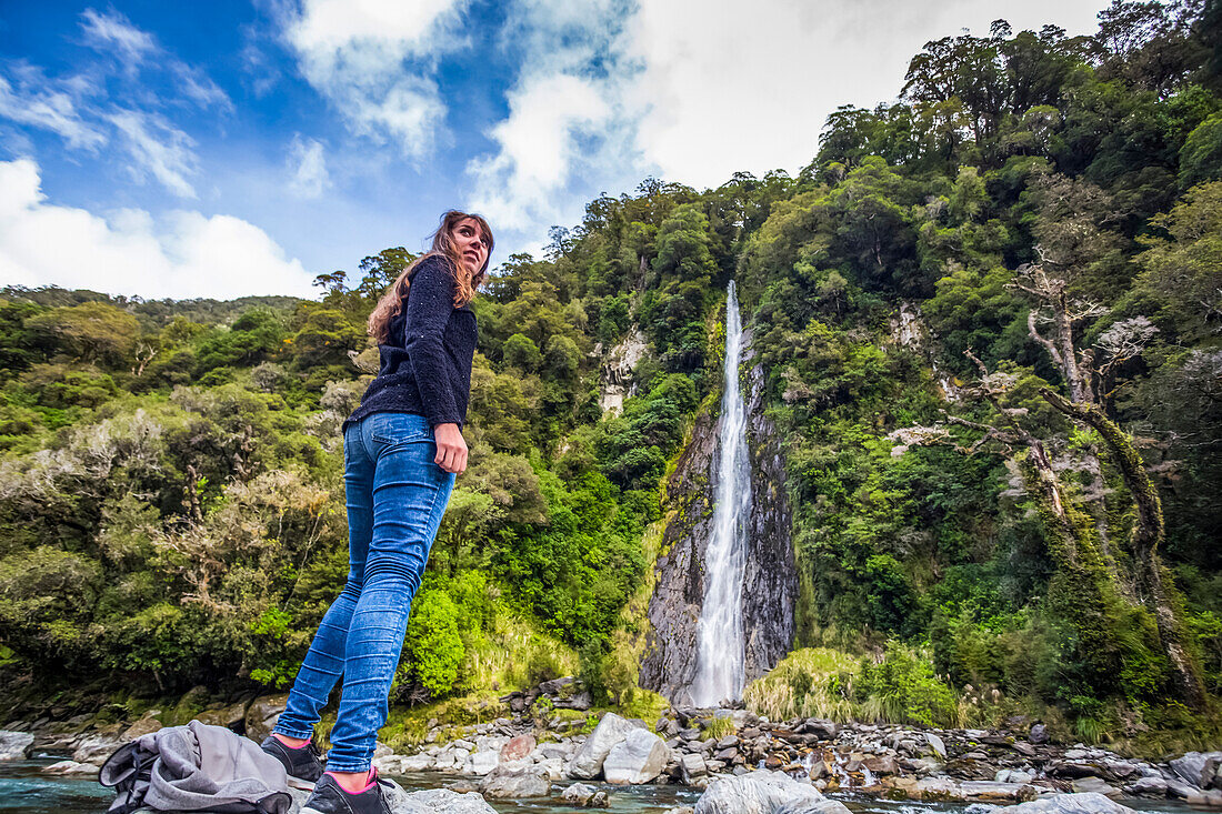 Tourist explores a random waterfall in a remote region of New Zealand's South Island; New Zealand