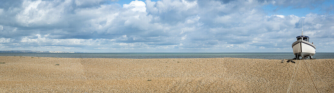 Wooden cabin boat tethered on the shingle beach at Dungeness along the Atlantic Coast; Dungeness, Kent, England, United Kingdom