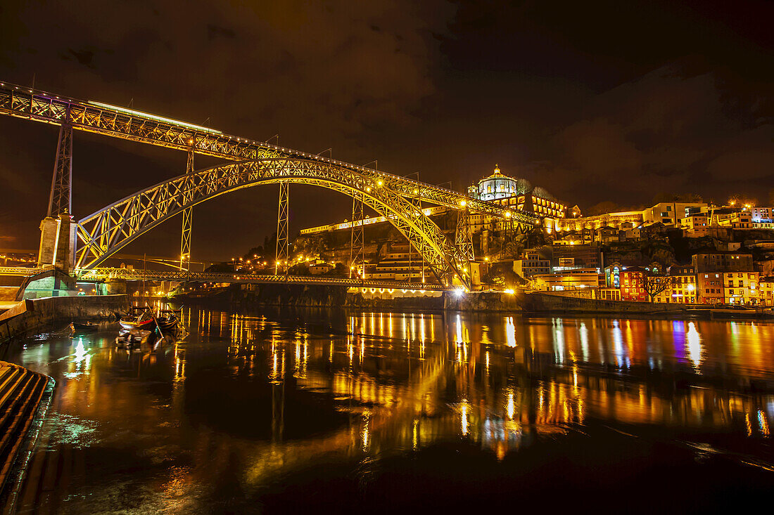 Brücke Dom Luis I über den Fluss Douro zwischen den Städten Porto und Vila Nova de Gaia, Blick auf das Kloster aus dem 17. Jahrhundert, Mosteiro da Serra de Pilar und die nächtlich beleuchteten Hafenlager von Vila Nova de Gaia; Porto, Region Norte, Portugal.