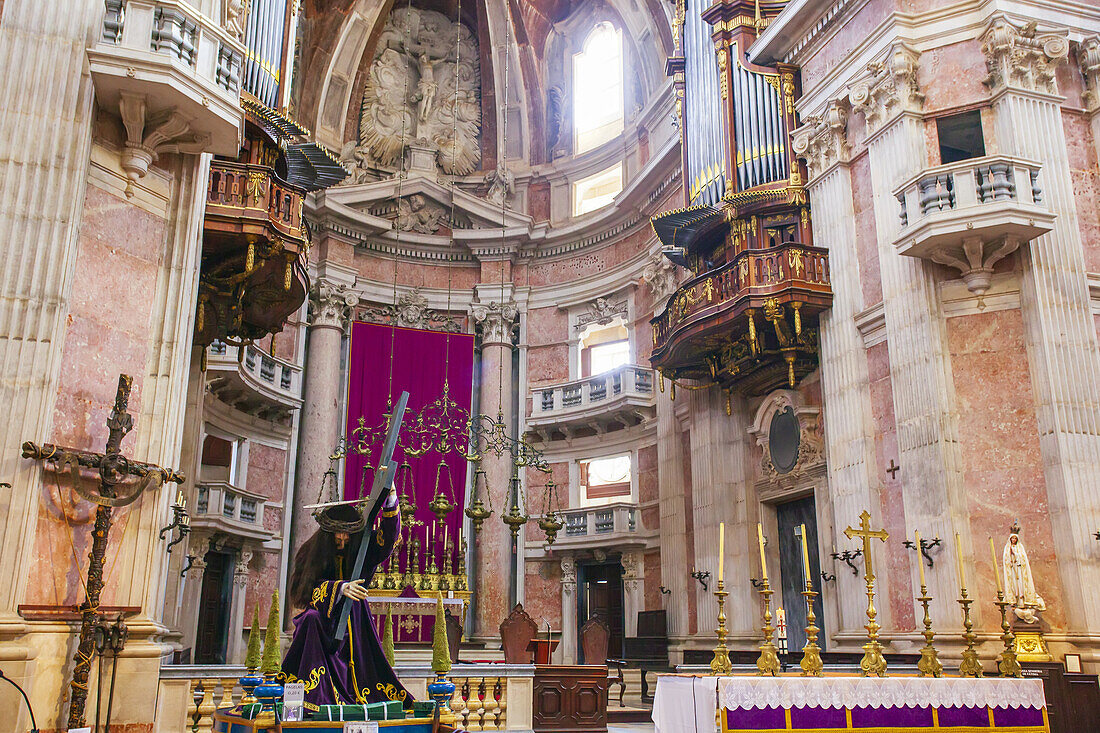 Der reich verzierte Hauptaltar der Basilika des Palastes und Klosters von Mafra mit einer historischen Pfeifenorgel darüber und einer Skulptur, die den unter dem Kreuz knienden Jesus in der Passion Christi darstellt; Mafra, Bezirk Lissabon, Region Lisboa, Portugal.