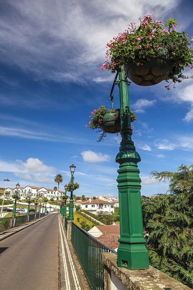 Mit blühenden Pflanzen gefüllte Laternenpfähle säumen die Straße und die historische Brücke in der malerischen Stadt Nordeste; Insel Sao Miguel, Azoren