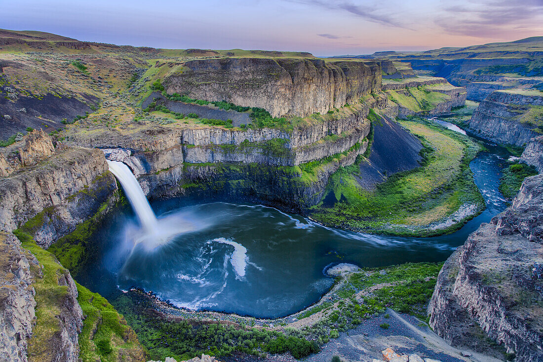 Overview of the Palouse Falls surrounded by basalt rock, a remnant of ancient glacial floods and lying on the Palouse River within the Palouse Falls State Park at sunset; Washington, United States of America