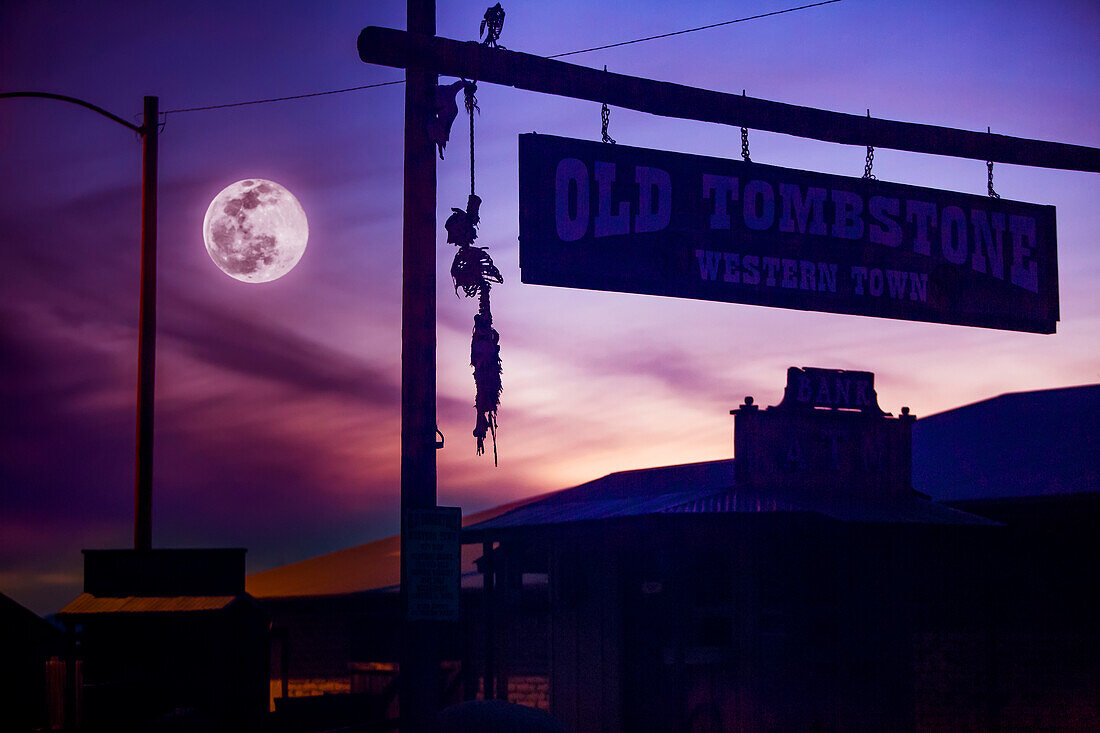 Silhouette of a skeleton hanging from the famed, western town of Tombstone with a full moon in a moody, purple sky; Tombstone, Cochise County, Arizona, United States of America