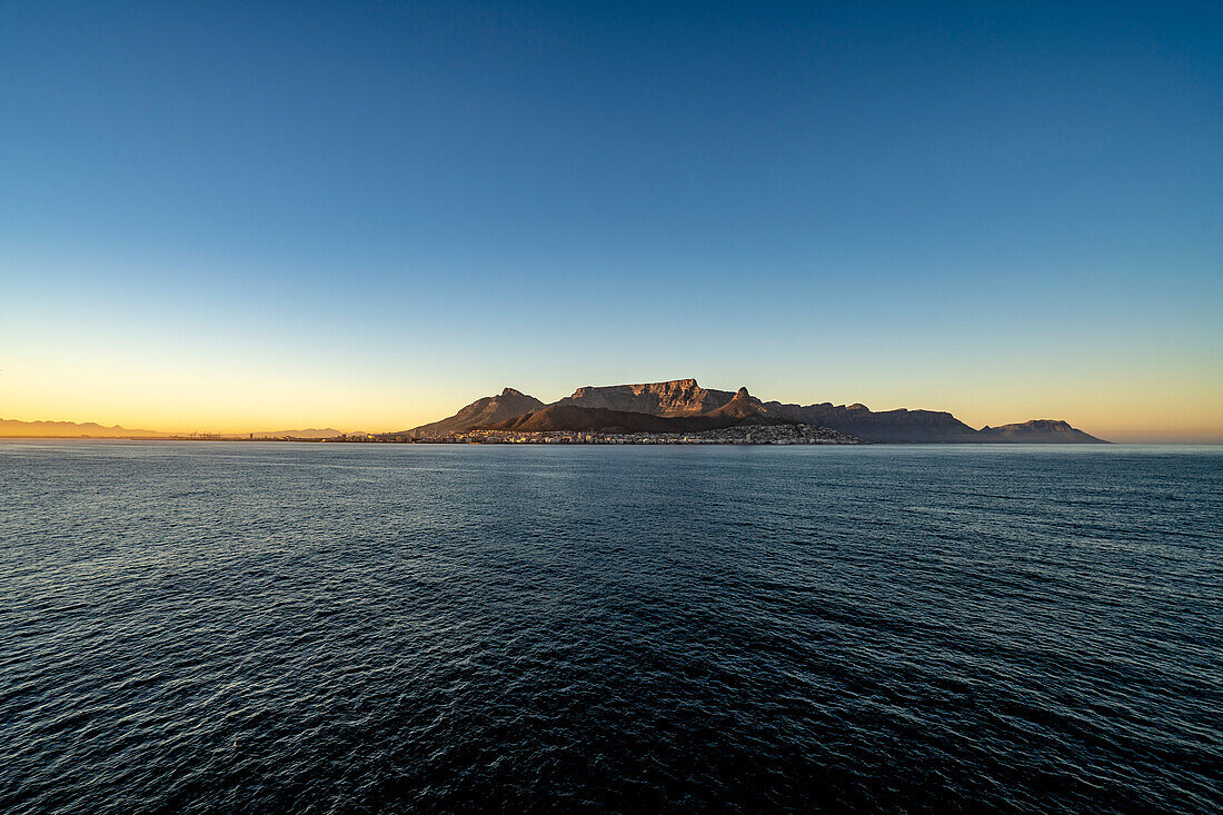 Dramatic view of Devil's Peak, Table Mountain and the Cape Town skyline at dawn rising from the sea; Cape Town, Cape Province, South Africa