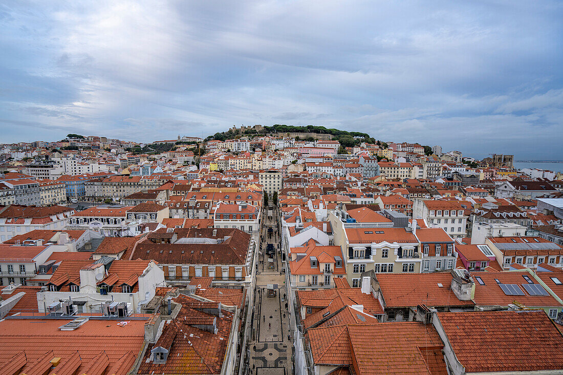 Überblick über die Altstadt der portugiesischen Hauptstadt Lissabon mit ihren pastellfarbenen Gebäuden und Ziegeldächern und der St. Georgs-Burg (Castelo de Sao Jorge) auf der Hügelspitze im Hintergrund; Lissabon, Portugal.