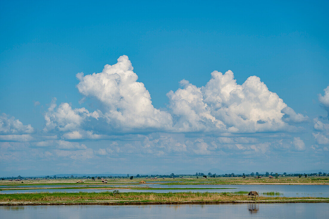 Wolken über den Ufern des Ayeyarwady (Irrawaddy) mit Hütten entlang des Ufers; Kachin-Staat, Myanmar (Burma)