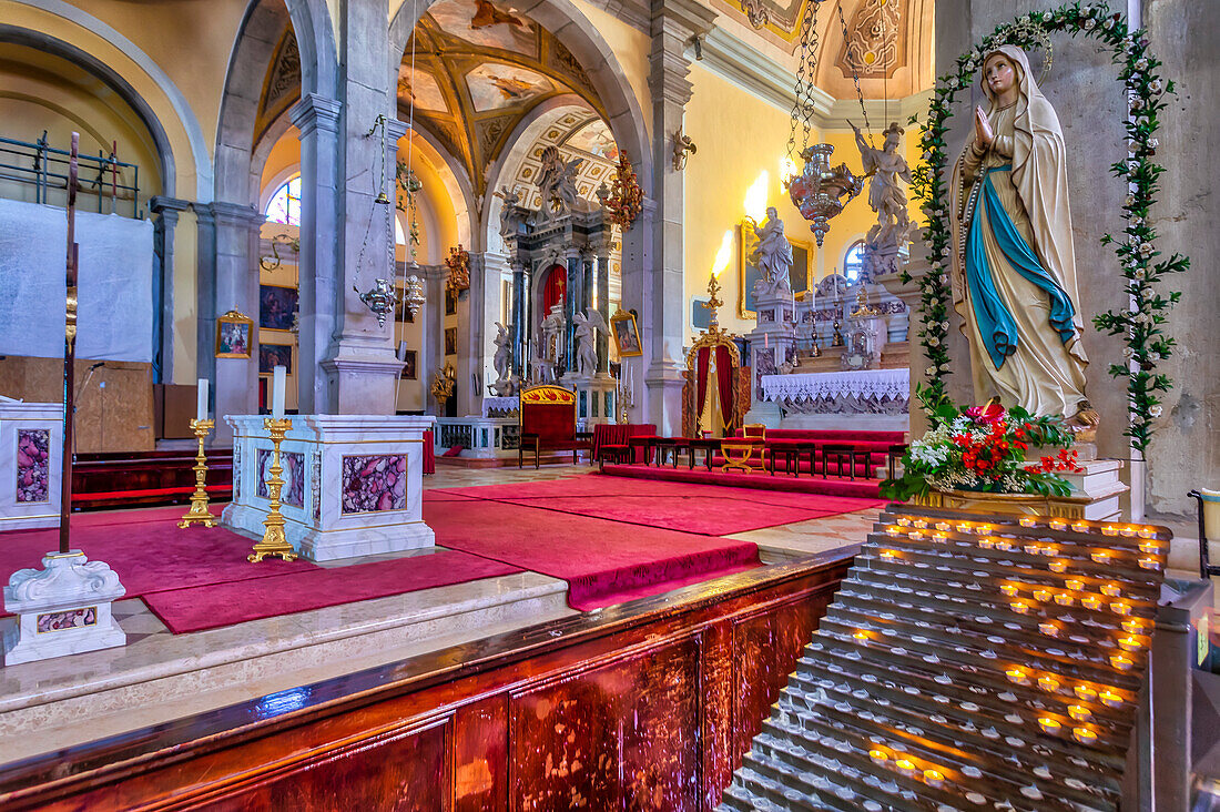 Das Innere der Kirche St. Euphemia zeigt eine religiöse Statue und Kerzen, die für Gebete und Intentionen angezündet werden, mit einem kunstvollen Hauptaltar im Hintergrund; Rovinj, Istrien, Kroatien.