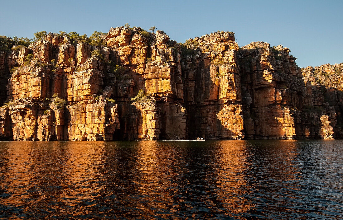 Expeditionsreisende an Bord von Schlauchbooten erkunden den Sandsteinhang mit seinen zerklüfteten Felsklippen entlang des King George River in der Kimberley-Region; Westaustralien, Australien