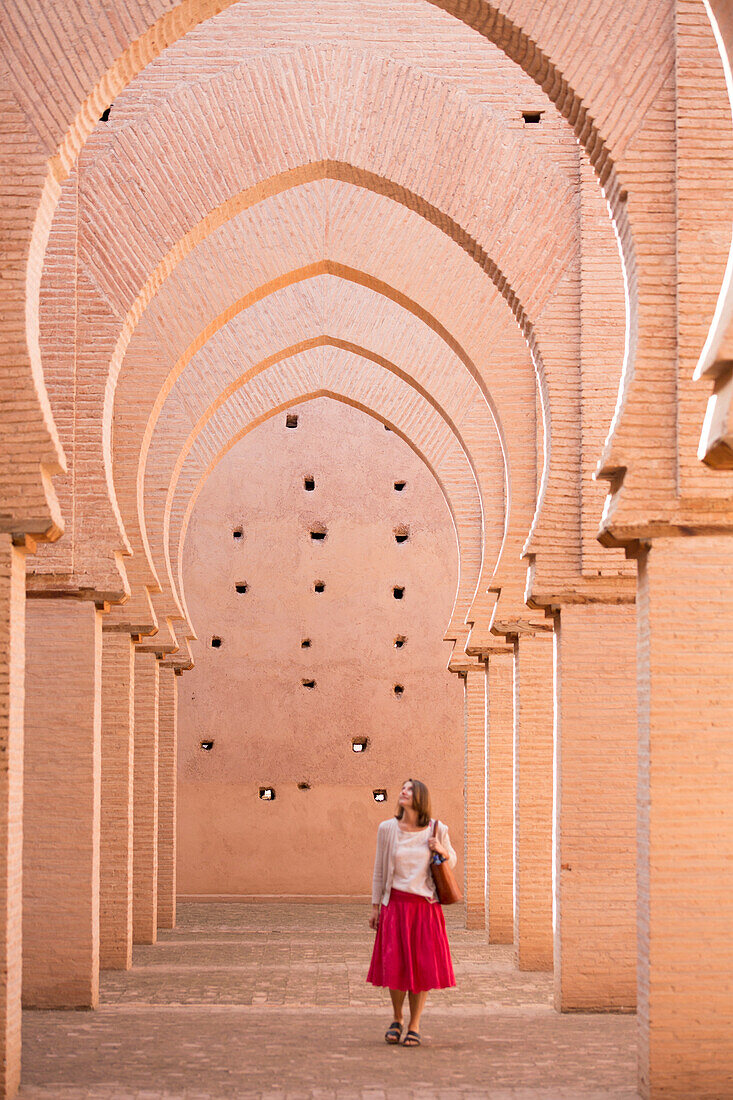 Woman traveler tours the pointed horseshoe arches of the 12th century Tinmal Almohad Mosque; Tinmal Village, High Atlas Mountains, Morocco