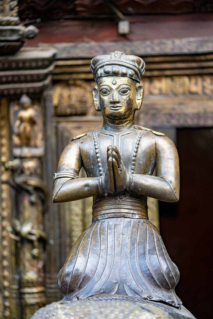 Nahaufnahme einer Messingstatue einer betenden Figur im Goldenen Tempel Kwa Bahal in der alten Stadt Patan oder Lalitpur, erbaut im zwölften Jahrhundert von König Bhaskar Varman im Kathmandutal; Patan (Lalitpur), Kathmandutal, Nepal.