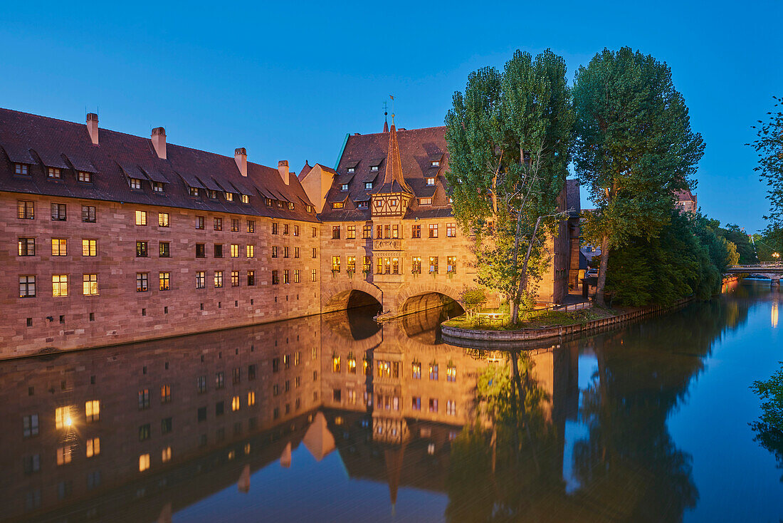 Pegnitz River flowing through Nuremberg at blue hour with the Heilig-Geist-Spital (Holy Spirit Hospital) in the Old Town; Franconia, Bavaria, Germany