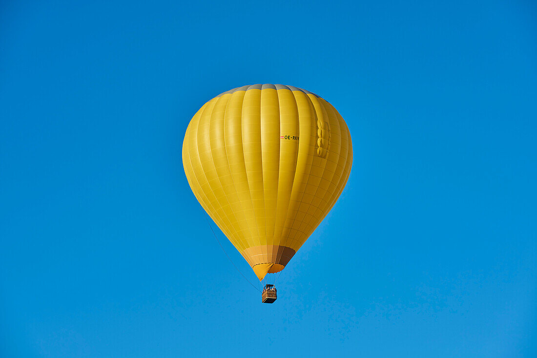 Yellow hot-air balloon in a clear, blue sky; Bavaria, Germany