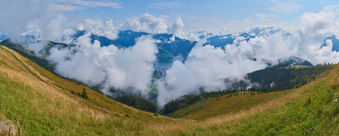 View from Mount Schüttenhöhe with clouds in the mountains above Zell am See, Kaprun; Salzburg State, Austria